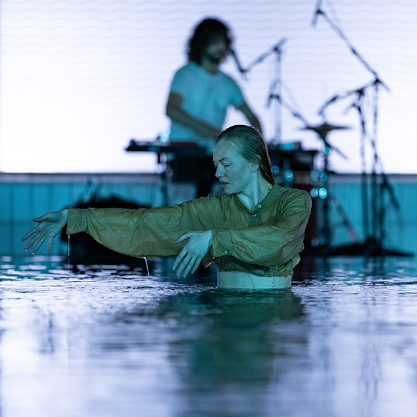 Dancer in a pool with drummer in the background
